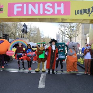 Runners in fancy dress costumes are stood underneath the finish line of the London Landmarks Half Marathon.