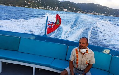 UKOT Conservation Officer Amdeep Sanghera sitting on a ferry as it pulls away from an island